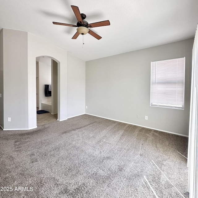 7117 W Globe Ave, Phoenix, AZ 85043 - spare room featuring carpet floors, arched walkways, a ceiling fan, and baseboards