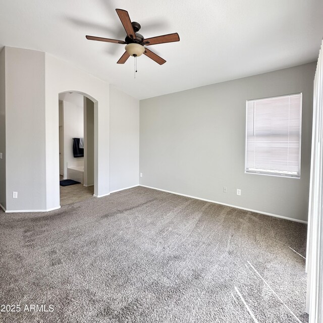 7117 W Globe Ave, Phoenix, AZ 85043 - spare room featuring carpet floors, arched walkways, a ceiling fan, and baseboards
