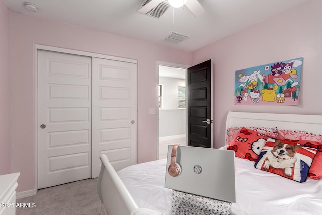 bedroom with visible vents, light colored carpet, a closet, and a ceiling fan