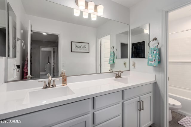 bathroom featuring double vanity, toilet, a bathtub, and a sink