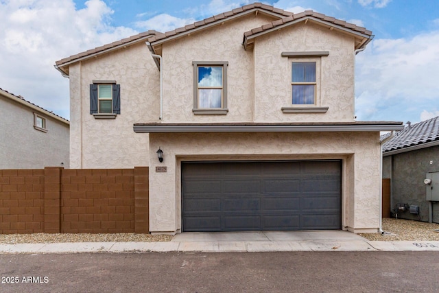 view of front of house with stucco siding, an attached garage, and fence