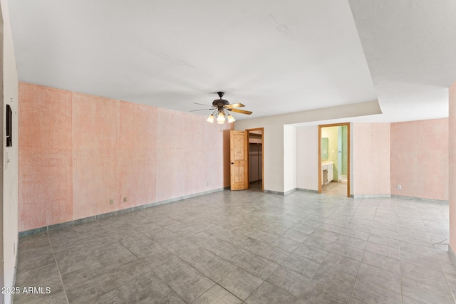 unfurnished room with ceiling fan and wood walls