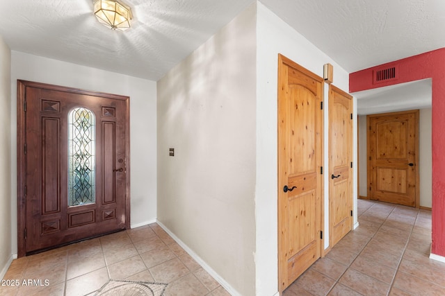 foyer featuring light tile patterned floors and a textured ceiling