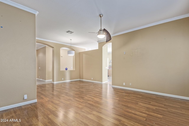 empty room with ornamental molding, wood-type flooring, and ceiling fan