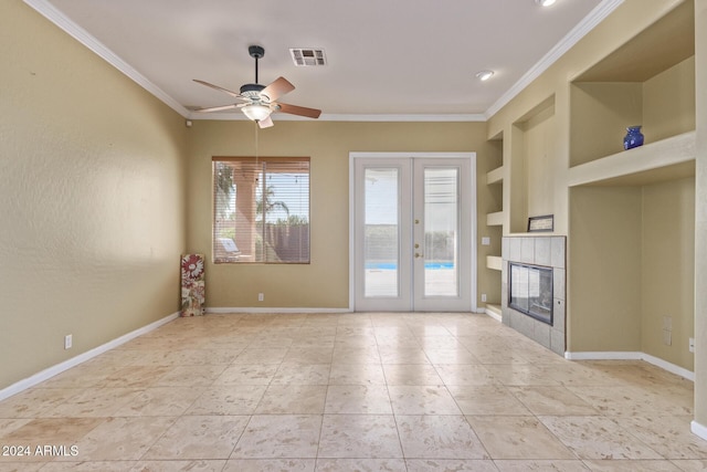 unfurnished living room featuring crown molding, a fireplace, built in features, and french doors