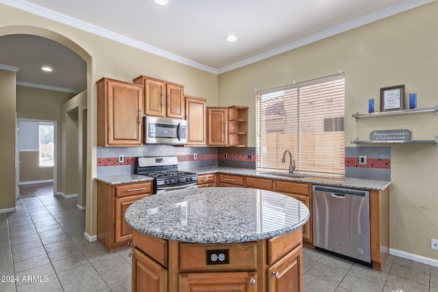 kitchen featuring a kitchen island, sink, light tile patterned floors, stainless steel appliances, and crown molding