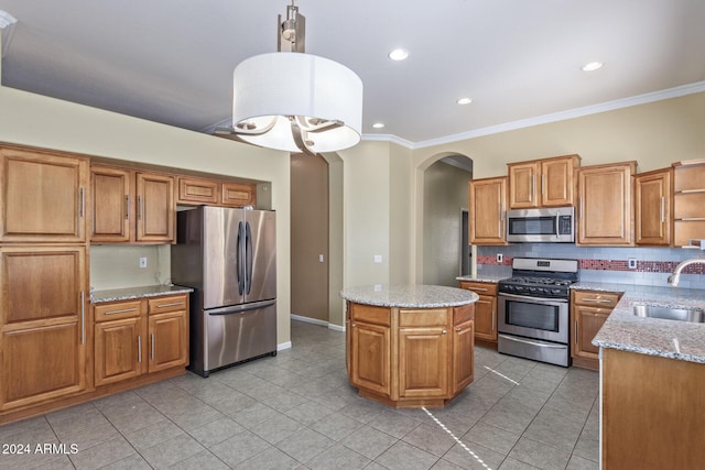 kitchen with sink, crown molding, stainless steel appliances, a kitchen island, and decorative light fixtures