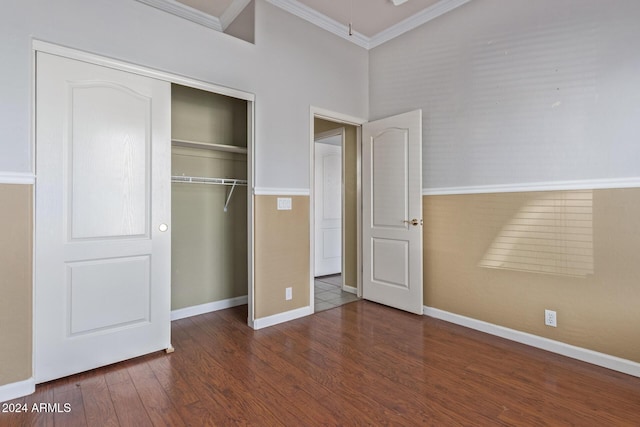 unfurnished bedroom with dark hardwood / wood-style flooring, crown molding, and a closet