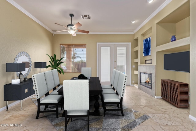 dining area featuring a fireplace, ceiling fan, crown molding, built in shelves, and french doors