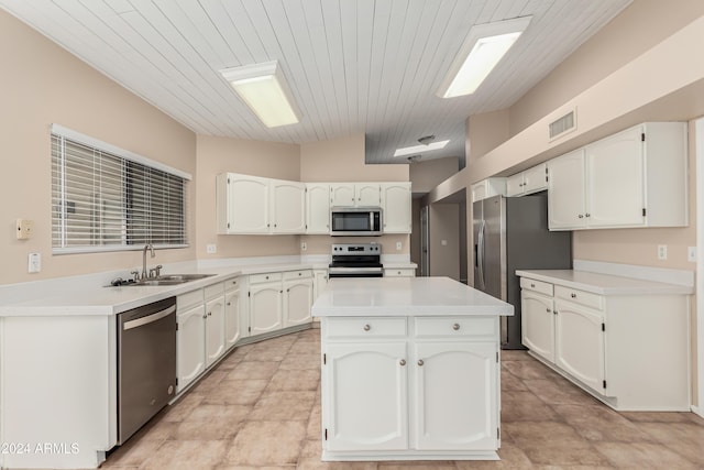 kitchen featuring stainless steel appliances, sink, white cabinetry, a kitchen island, and lofted ceiling