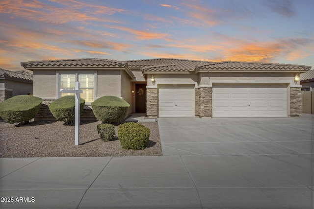 view of front of house with a garage, stone siding, concrete driveway, and stucco siding