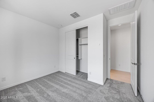 unfurnished bedroom featuring light carpet and a closet