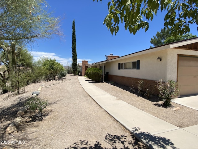 1455 W Kenrick Dr, Wickenburg, AZ 85390 - view of side of home featuring stucco siding, brick siding, and a chimney