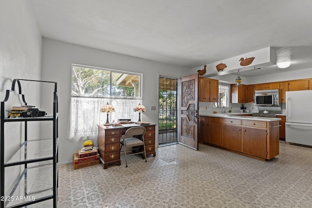 1455 W Kenrick Dr, Wickenburg, AZ 85390 - kitchen featuring freestanding refrigerator, light countertops, stainless steel microwave, brown cabinets, and an office area
