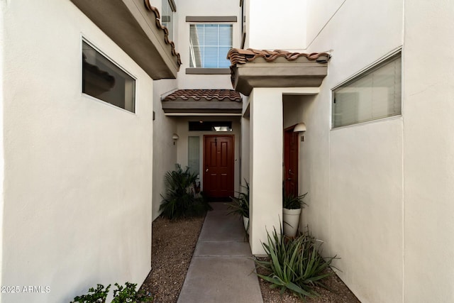 view of exterior entry featuring a tile roof and stucco siding