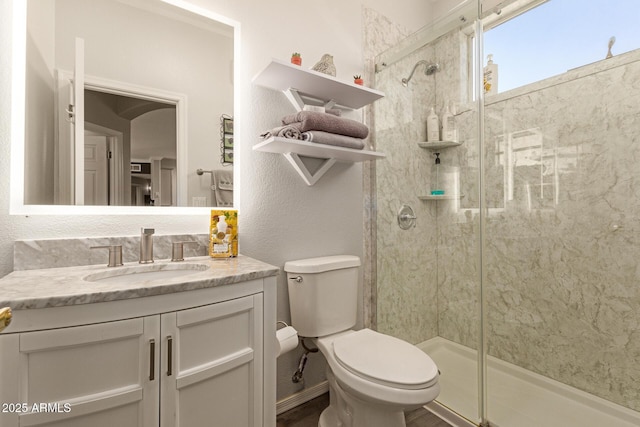 bathroom with a shower stall, toilet, and vanity