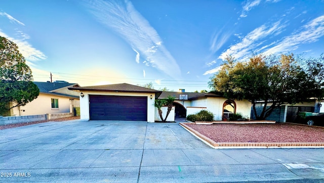 single story home with a garage, concrete driveway, fence, and stucco siding