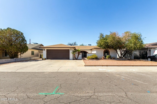 ranch-style house featuring a garage, concrete driveway, fence, and stucco siding