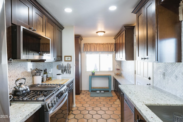 kitchen with dark brown cabinets, stainless steel appliances, light stone counters, and decorative backsplash