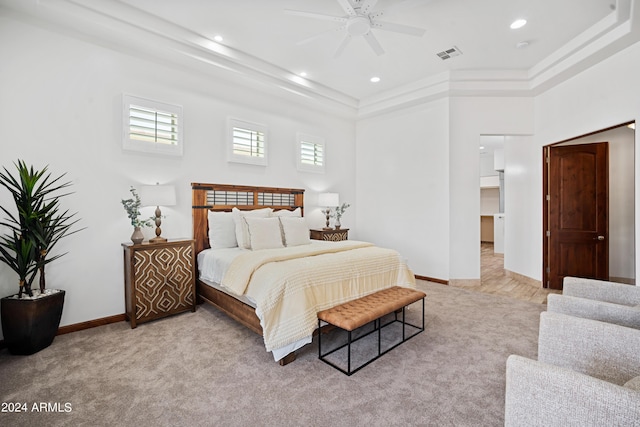 carpeted bedroom with a raised ceiling and ceiling fan