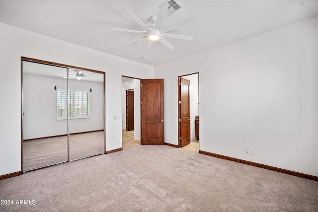 unfurnished bedroom featuring connected bathroom, light colored carpet, and ceiling fan