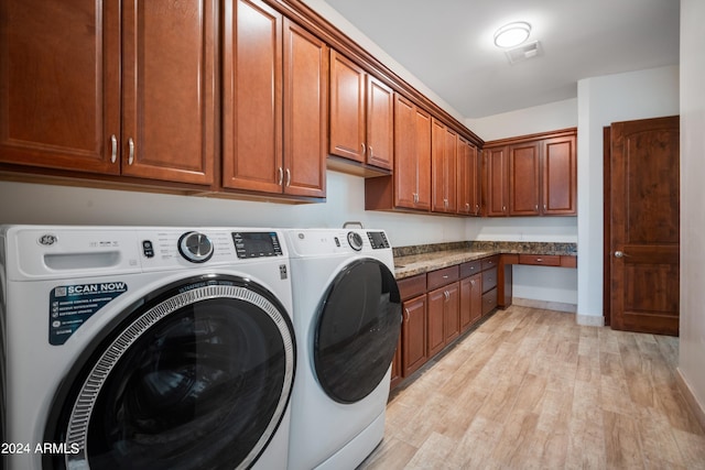 laundry area with cabinets, light wood-type flooring, and washing machine and clothes dryer