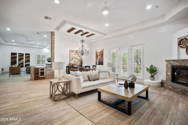 living room with a fireplace, light hardwood / wood-style floors, and ceiling fan with notable chandelier