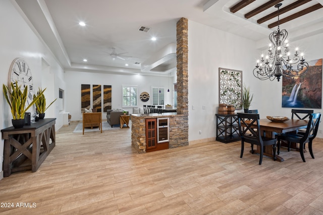 dining room featuring ceiling fan with notable chandelier, light hardwood / wood-style floors, and a tray ceiling