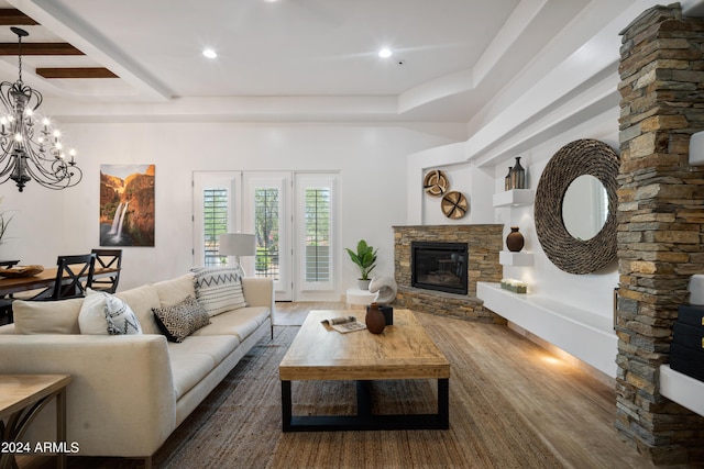 living room featuring dark hardwood / wood-style floors, a stone fireplace, and a notable chandelier