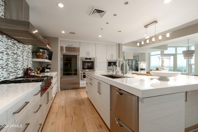 kitchen with white cabinetry, decorative light fixtures, ventilation hood, and appliances with stainless steel finishes