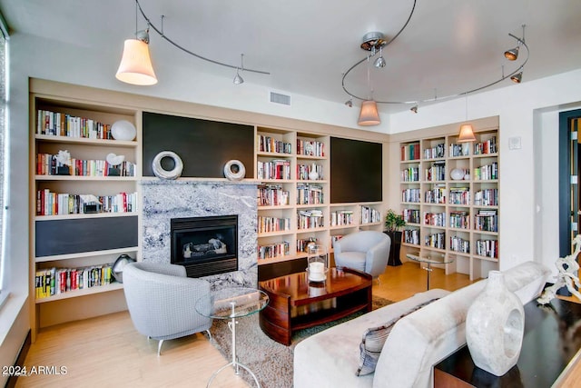 sitting room with built in shelves, a fireplace, and wood-type flooring