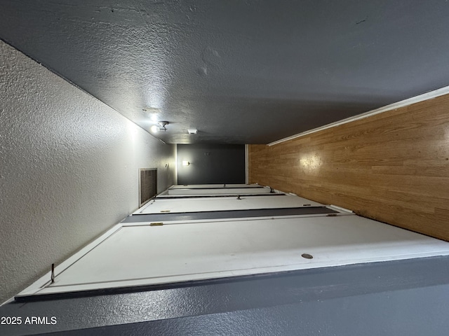 corridor featuring a textured wall and a textured ceiling