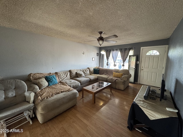 living area with a textured wall, ceiling fan, wood finished floors, and a textured ceiling