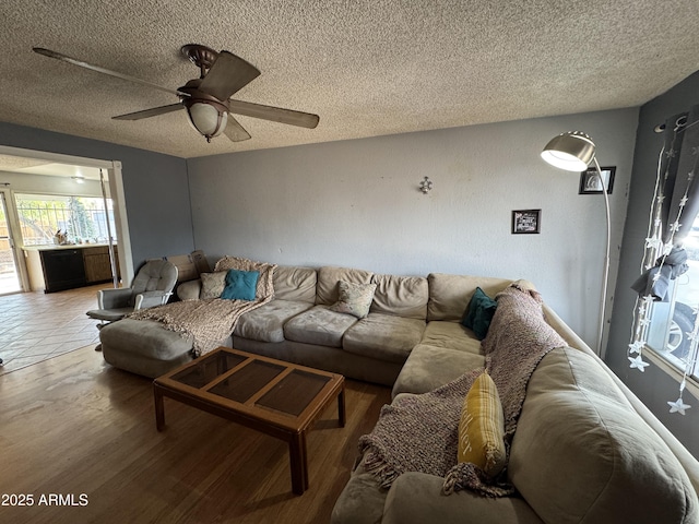 living room featuring a textured ceiling, wood finished floors, and ceiling fan