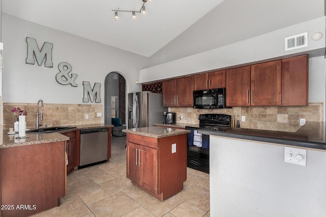 kitchen with arched walkways, lofted ceiling, visible vents, a kitchen island, and black appliances