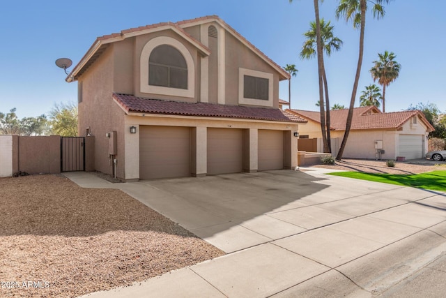 view of front of house with a garage, concrete driveway, a tile roof, a gate, and stucco siding