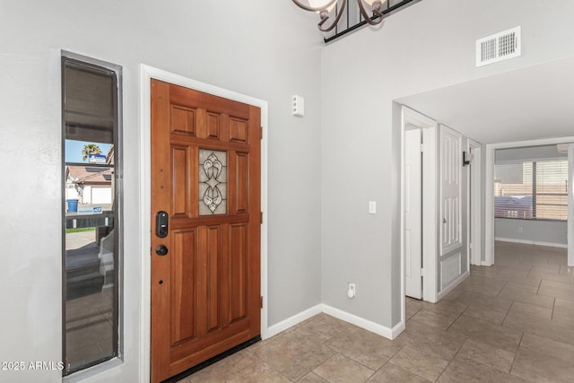 foyer featuring an inviting chandelier, visible vents, and baseboards