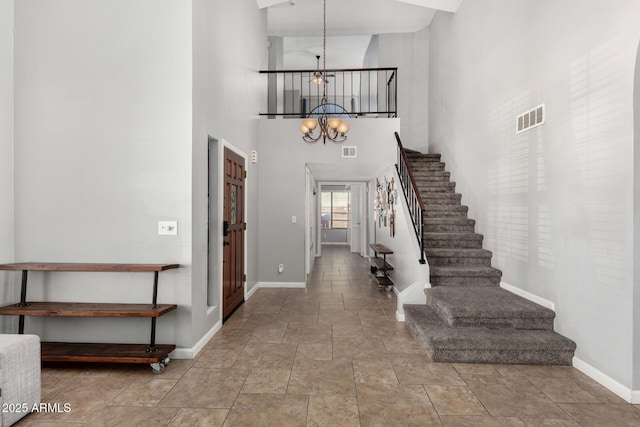 entryway with a chandelier, visible vents, baseboards, and stairs