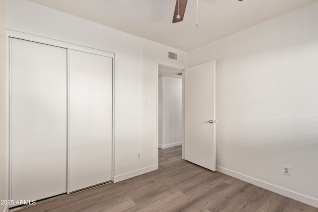 unfurnished bedroom featuring ceiling fan, light hardwood / wood-style floors, and a closet