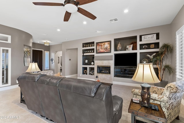 living room with built in shelves, ceiling fan, and a fireplace