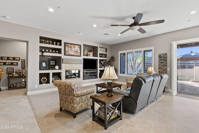 living room featuring a fireplace, built in features, ceiling fan, and light tile patterned flooring