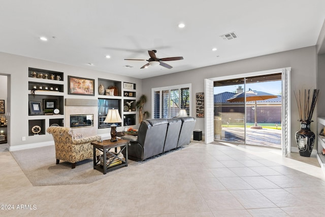 tiled living room with built in shelves and ceiling fan