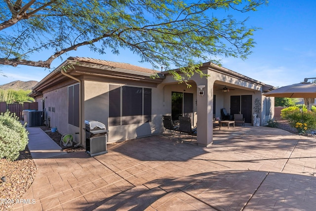 back of house with ceiling fan, a mountain view, a patio, and central AC