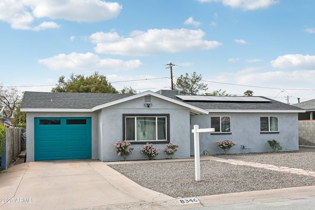 ranch-style house featuring stucco siding, roof with shingles, fence, a garage, and roof mounted solar panels