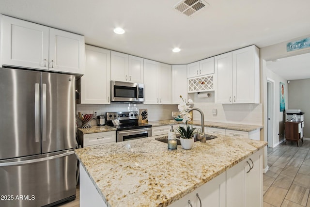 kitchen with a sink, stainless steel appliances, tasteful backsplash, and visible vents