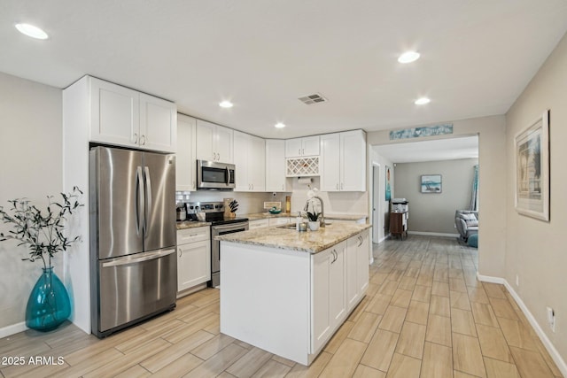 kitchen with white cabinetry, light stone countertops, a sink, and stainless steel appliances