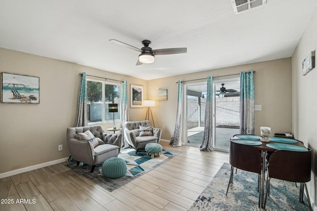 living area with baseboards, visible vents, a ceiling fan, and light wood finished floors