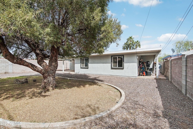 rear view of property with stucco siding and fence