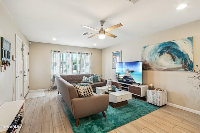 living area featuring baseboards, visible vents, ceiling fan, and wood finish floors