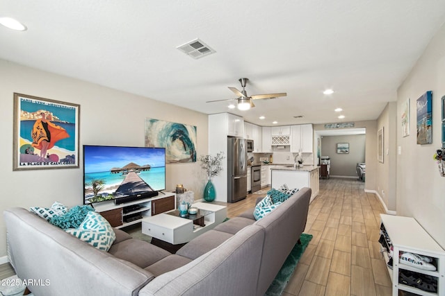 living room with a ceiling fan, wood finish floors, baseboards, visible vents, and recessed lighting